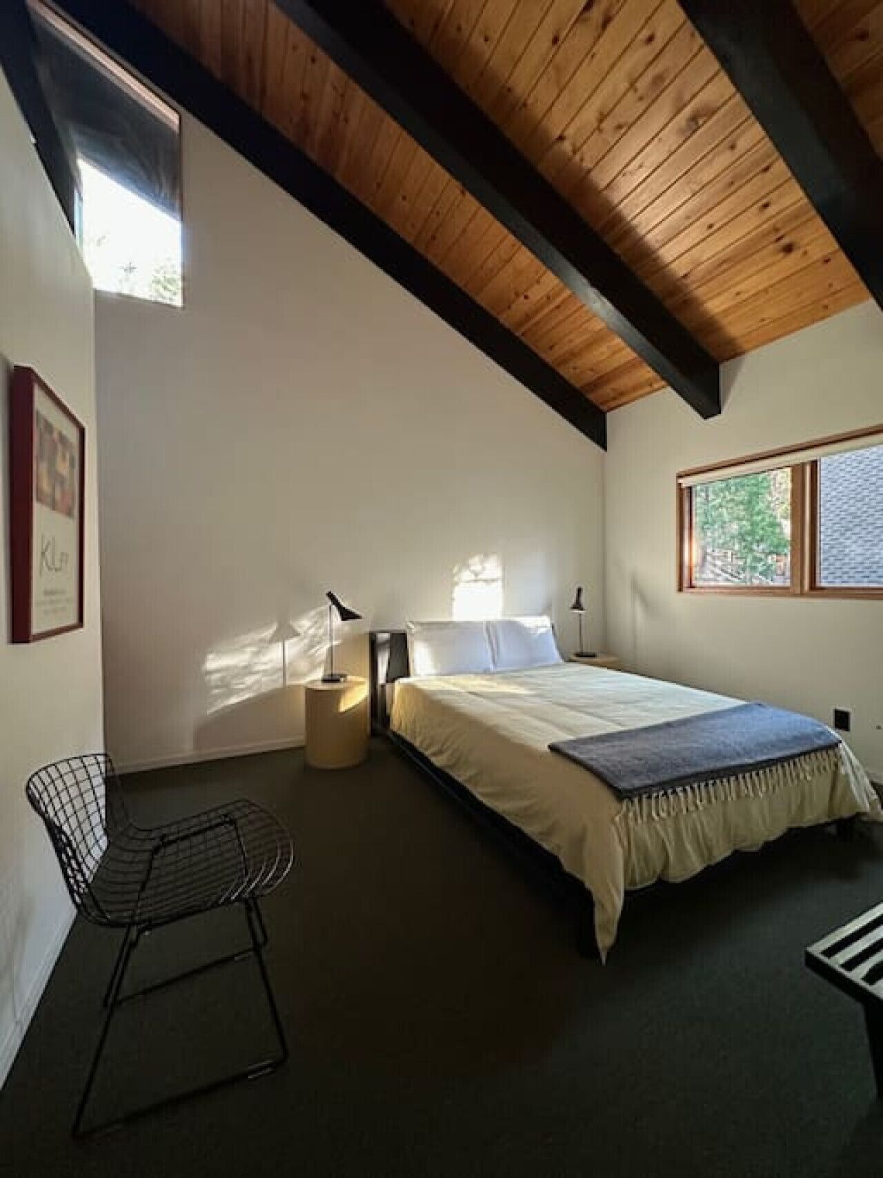 Un dormitorio con cama, una silla, una mesita de noche y una ventana.