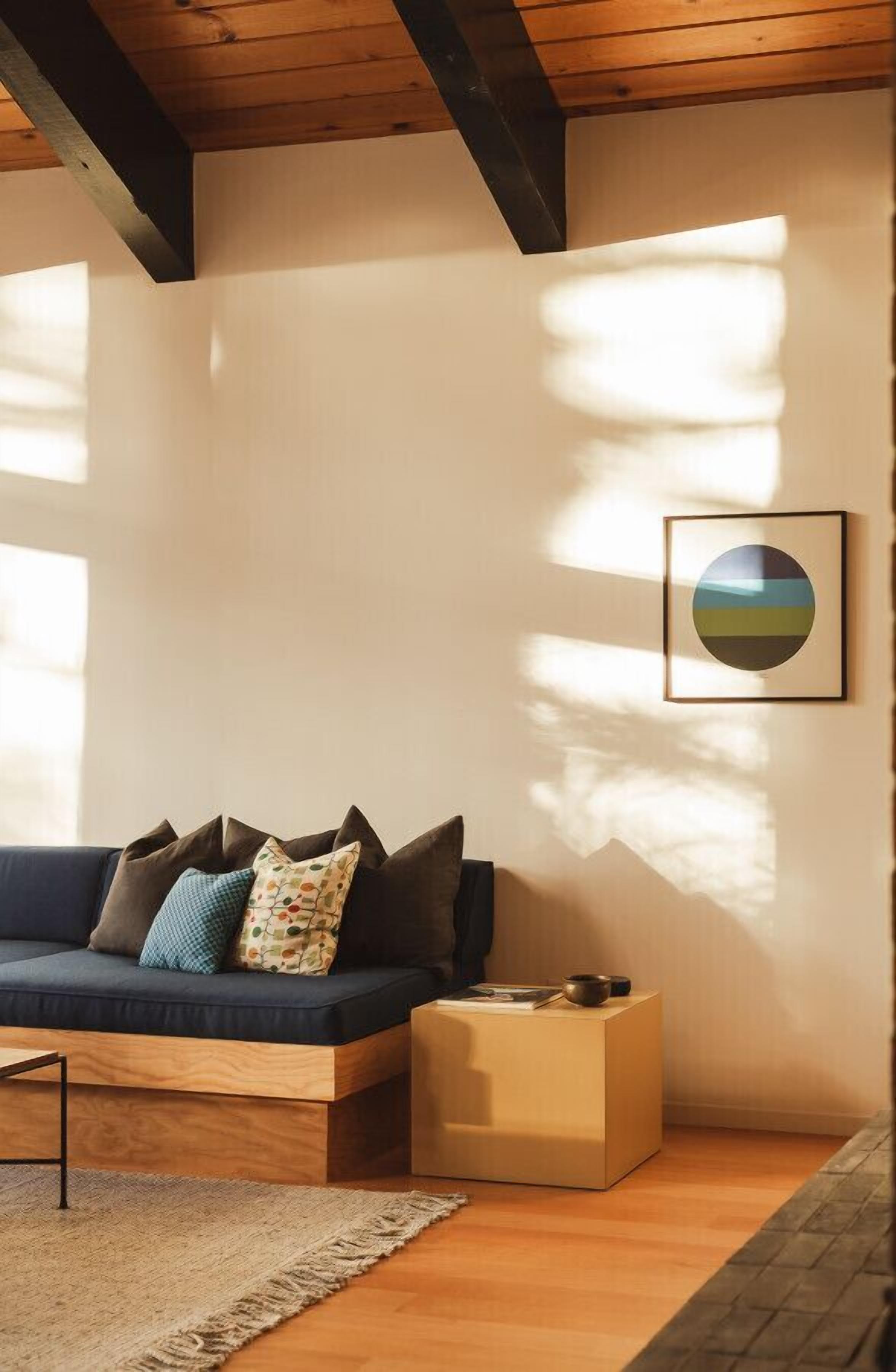 A modern living room with a dark blue sofa, a wooden coffee table, and a framed picture on the wall.