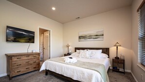 A bedroom with a bed, a dresser, two bedside lamps, and two wall-mounted paintings. - Cozy Comfy Condo MH107| Near Powder Mtn | Hot Tub (Eden)