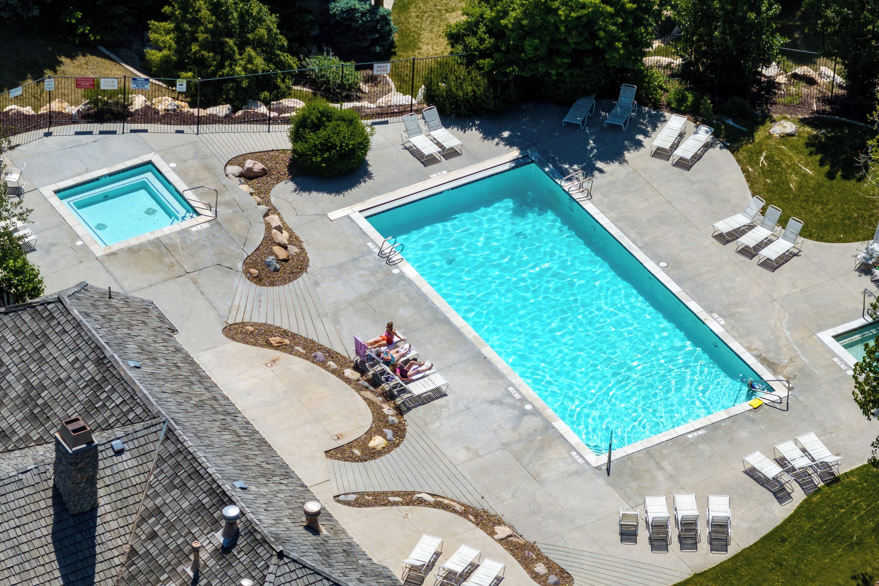 A large rectangular pool with a surrounding deck, lounge chairs, and a smaller adjacent pool.
