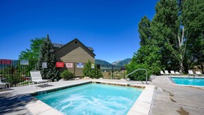 A pool area with a hot tub, lounge chairs, and a spa capacity sign. - Basin Lakeside Getaway MH702|Near Powder Mtn |Hot Tub (Eden)