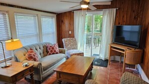A living room with a sofa, armchair, coffee table, TV stand, and a ceiling fan. - Porch Swing Place - Newly Renovated Charm
 (Springfield)