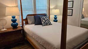A four-poster bed with a wooden headboard, two bedside lamps, and a patterned throw pillow. - Porch Swing Place - Newly Renovated Charm
 (Springfield)