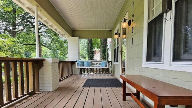 A covered porch with wooden flooring, a bench, and a table with chairs. - Porch Swing Place - Newly Renovated Charm
 (Springfield)