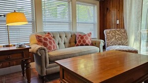A living room with a sofa, armchair, wooden coffee table, and a lamp. - Porch Swing Place - Newly Renovated Charm
 (Springfield)