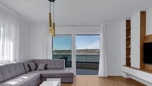 A modern living room with a grey sectional sofa, a white coffee table, and a large TV on a wooden shelf. - Villa VIP with heaed swimming pool and 4 Bedrooms, Several terraces with seaview (Makarska)