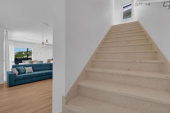 Un intérieur moderne avec un escalier, un canapé bleu et un coin repas.