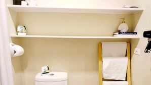 Een badkamer met toilet, een plank met toiletartikelen en een handdoekhouder.