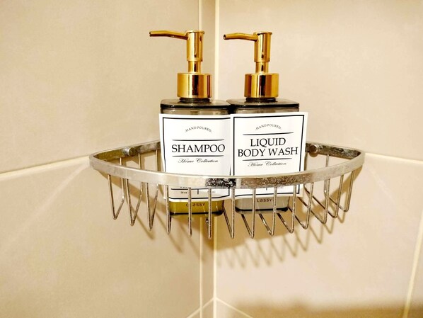 Estante de baño con dos botellas de champú y gel de ducha hechos a mano.