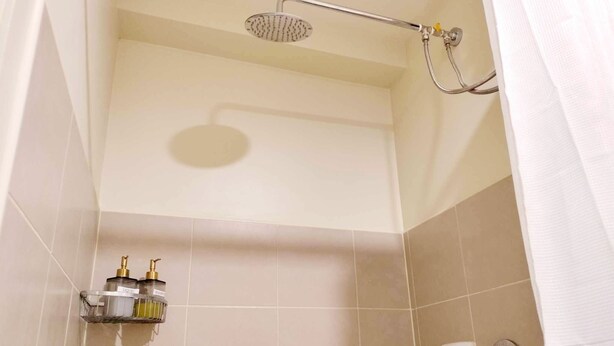 A shower area with a handheld showerhead, a wall-mounted hand dryer, and a soap dispenser. - Remarkable Modern 1-bed Apartment in Cebu City (Cebu City)