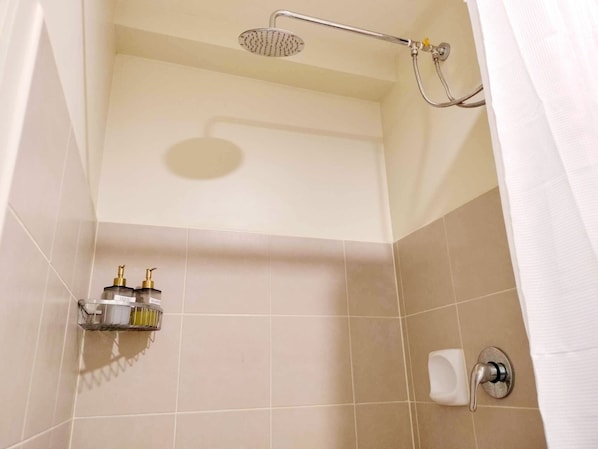 A shower area with a handheld showerhead, a wall-mounted hand dryer, and a soap dispenser. - Remarkable Modern 1-bed Apartment in Cebu City (Cebu City)
