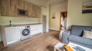 Une cuisine compacte équipée d’un lave-linge, d’un four à micro-ondes et d’un réfrigérateur.