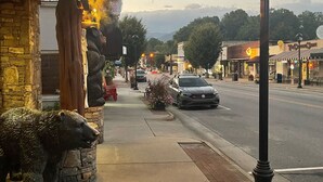 A street view with a stone building featuring a bear statue, a sidewalk, and a car on the road. - Brand new home less than one mile to Bryson City! (Bryson City)