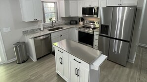 A modern kitchen with white cabinetry, stainless steel appliances, and a central island. - Brand new home less than one mile to Bryson City! (Bryson City)