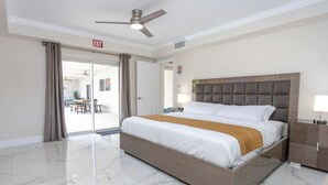 A hotel room with a large bed, a ceiling fan, a nightstand, and a view of the outside.
