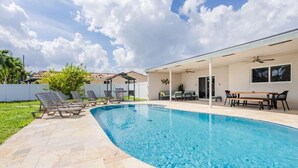 A swimming pool with lounge chairs and a covered patio area.