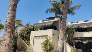 Ein Resort mit Palmen, einem Gebäude mit Reetdach und einer Hängematte.