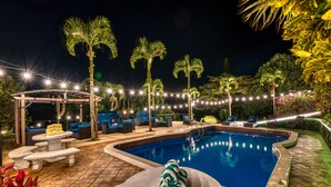 A poolside area with a pool, lounge chairs, and a pergola.