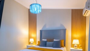 Un dormitorio moderno con una cama grande, dos mesitas de noche con lámparas, un aplique de techo y un panel de pared de madera.