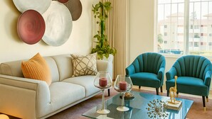 Una sala de estar moderna con un sofá, dos sillones, una mesita de centro y placas decorativas en la pared.