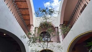 Une cour intérieure avec des arcades, une table, des chaises et un arbre.