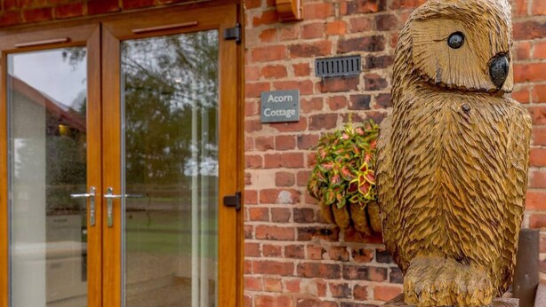 A rustic building with a wooden bear sculpture in front. - Charming 2-bed Cottage, Beautiful Views, Knutsford (Knutsford)
