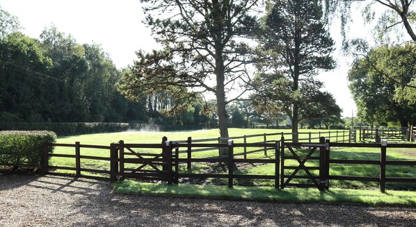 A fenced outdoor area with a gravel path, surrounded by trees and a grassy field. - Charming 2-bed Cottage, Beautiful Views, Knutsford (Knutsford)