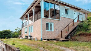 A two-story house with a brick exterior, large windows, and a staircase leading to the upper floor. - Charmante Villa Neuve à Trinité (La Trinité)