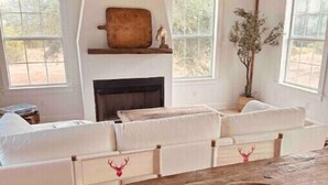 A rustic interior with a fireplace, white sofas, and a wooden table. - A Sanctuary of Stories! (Round Top)
