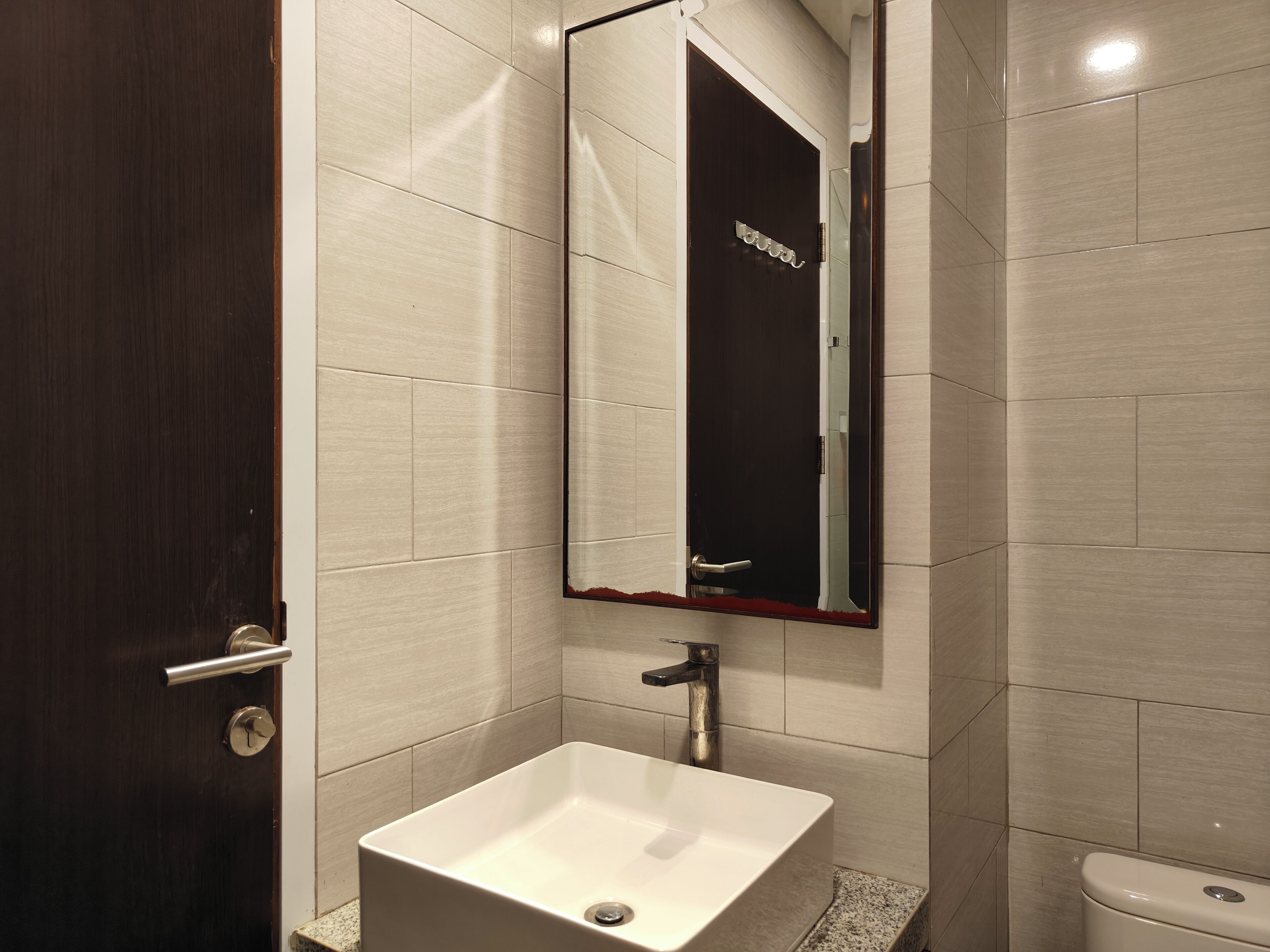 Ein Badezimmer mit einem weißen Waschbecken, einem Spiegel und einer Toilette.