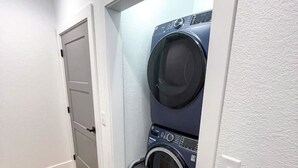 Ein Waschraum mit einer Waschmaschine und einem Trockner, einer Tür und einem Holzboden.