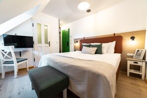 Ein Schlafzimmer mit einem Bett, einem Schreibtisch, einem Stuhl, einem Nachttisch und einer grünen Tür.