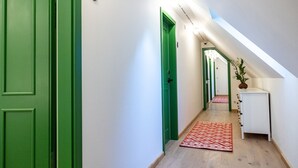 A hallway with green doors, a white console table, and a patterned rug. - Czakó Bed & Breakfast (Budapest)