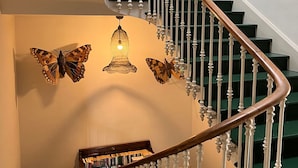 A staircase with white balusters and a wooden handrail, leading to a landing with a bookshelf and decorative butterflies. - Le Rouzet (Cazouls-les-Beziers)