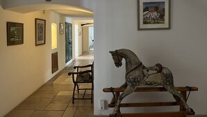 A hallway with framed artwork, a wooden rocking horse, and a mounted insect. - Le Rouzet (Cazouls-les-Beziers)