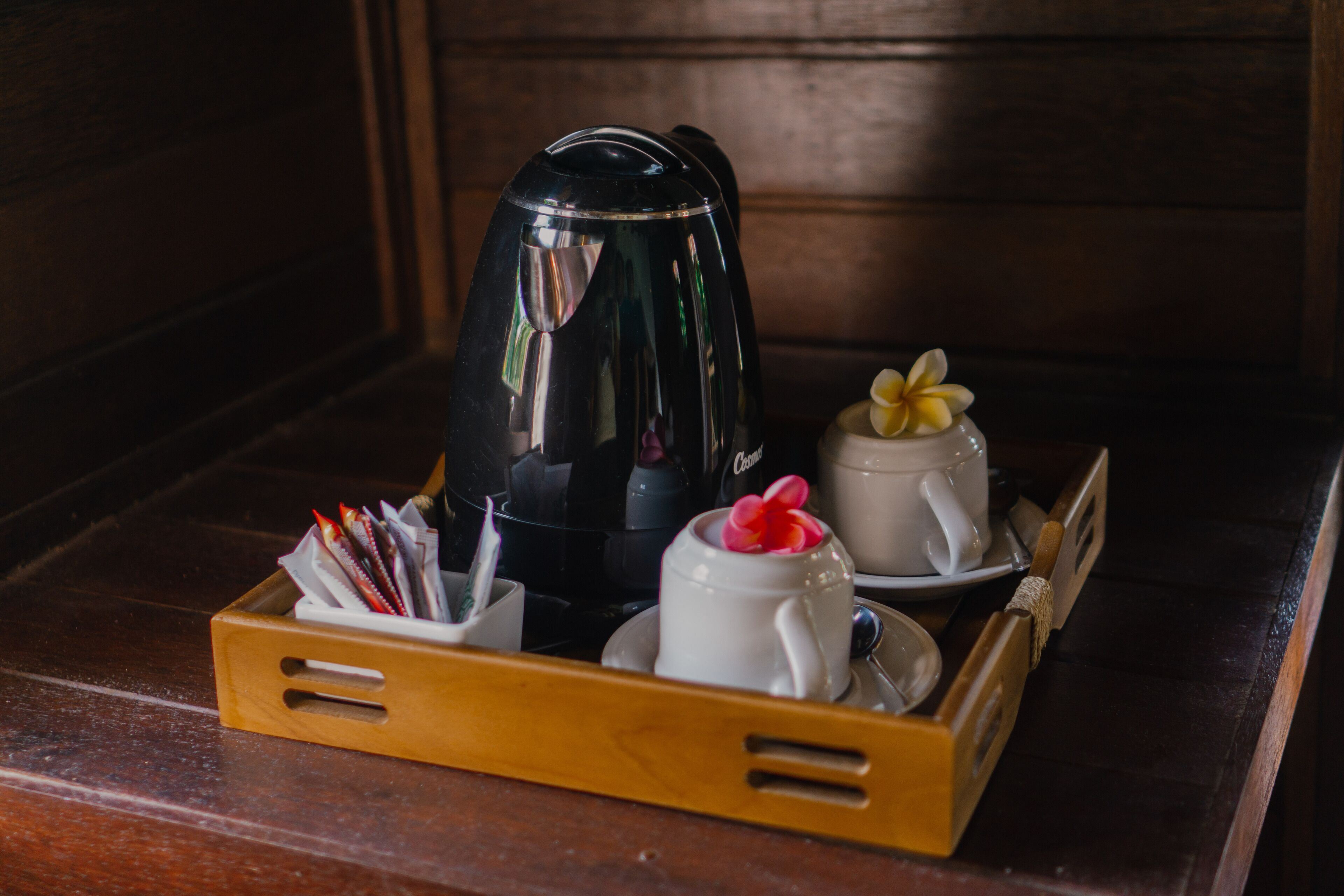 Un plateau avec une cafetière, une tasse blanche ornée d’une fleur et une tasse blanche avec sa soucoupe.