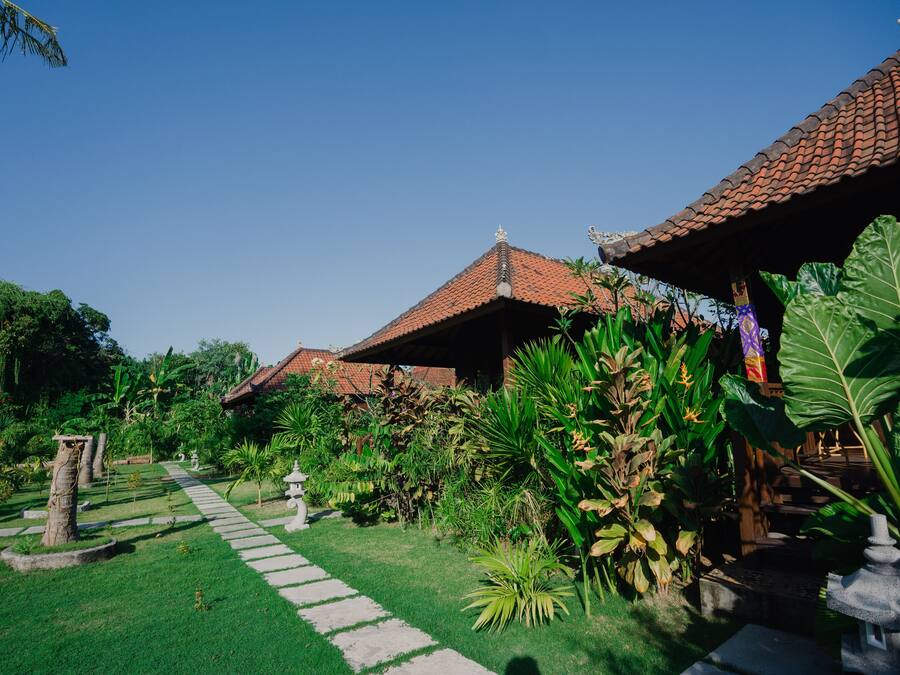 A traditional building with a tiled roof, surrounded by lush greenery and a stone pathway.