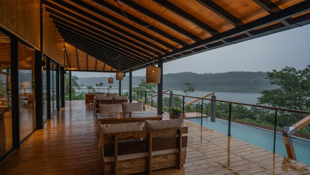 A wooden deck with outdoor seating and a view of a lake. - Reserva Natural Iguazú - Pristine Luxury Camp (Puerto Libertad)