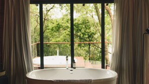 A circular bathtub in a room with wooden flooring and a thatched roof. - Reserva Natural Iguazú - Pristine Luxury Camp (Puerto Libertad)