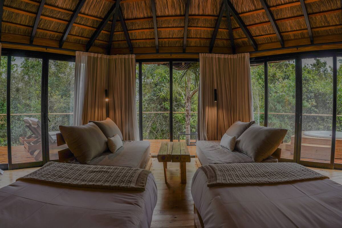 Une chambre avec deux lits, de grandes fenêtres et un plafond en bois.