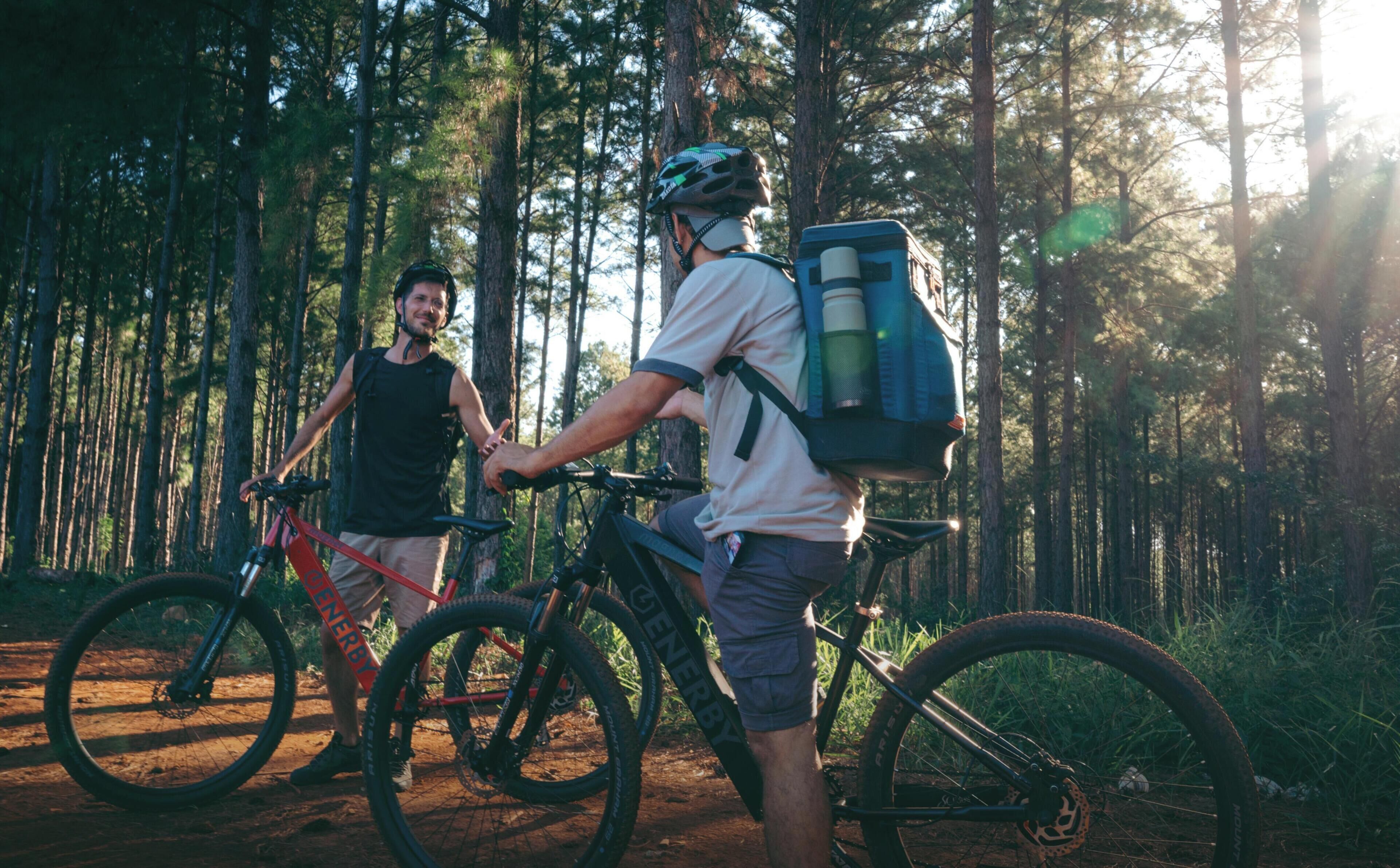 Due ciclisti in una foresta, uno con uno zaino.