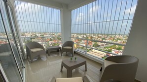 Ein Balkon mit Korbmöbeln, einem kleinen Tisch und Blick auf eine Stadtansicht.