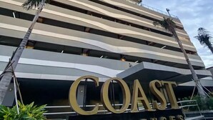 Een hoog gebouw met een opvallend, gebogen ontwerp, met de tekst 'COAST RESIDENCES'.