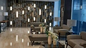 Een moderne lobby met banken, tafels en een decoratieve wand.