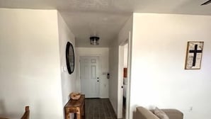 A hallway with a dining table and chairs, a sofa, and a small table with a basket.