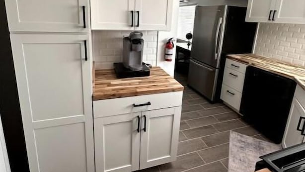 A kitchen with white cabinets, a coffee maker, and a refrigerator.