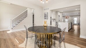 A spacious dining area with a round table, clear chairs, and a modern chandelier. - New Luxe Reno W/Hot Tub & Roof Top Terrace! (Columbus)