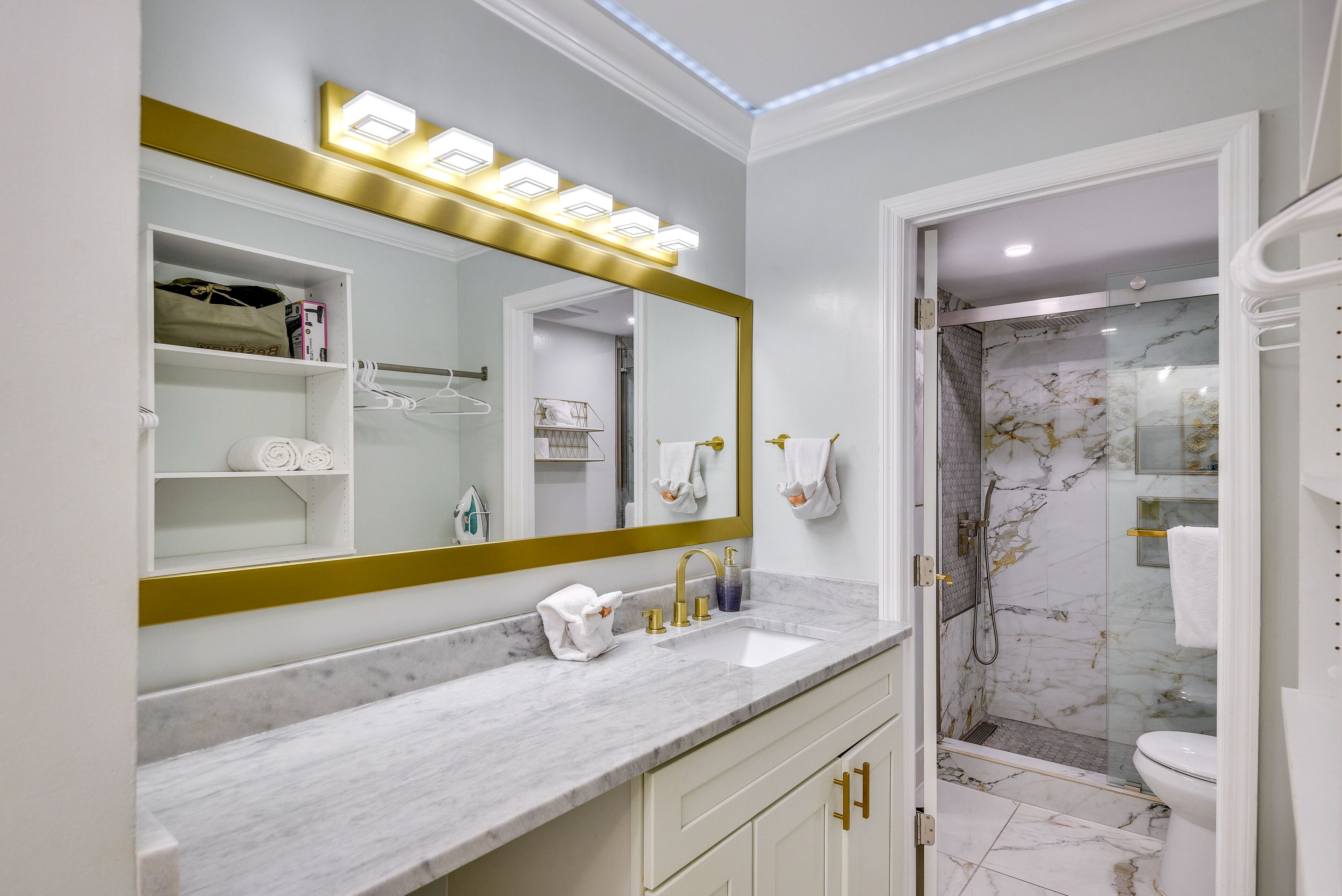 A modern bathroom with a large mirror, vanity, and a shower area.