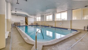 Ein Hallenbad mit klarem Wasser, einem Rettungsschwimmerstuhl und einer Sitzbank.