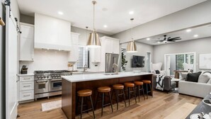 A modern kitchen with a central island, bar stools, stainless steel appliances, and pendant lighting. - New Build Hot Tub Dtown ShortNorth (Columbus)